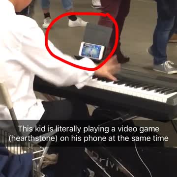 Kid white dress shirt playing piano in subway while playing hearthstone game on phone