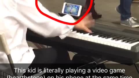 Kid white dress shirt playing piano in subway while playing hearthstone game on phone