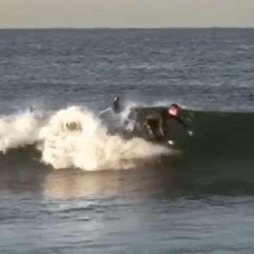 Wet suit surfer rides board towards dock falls off