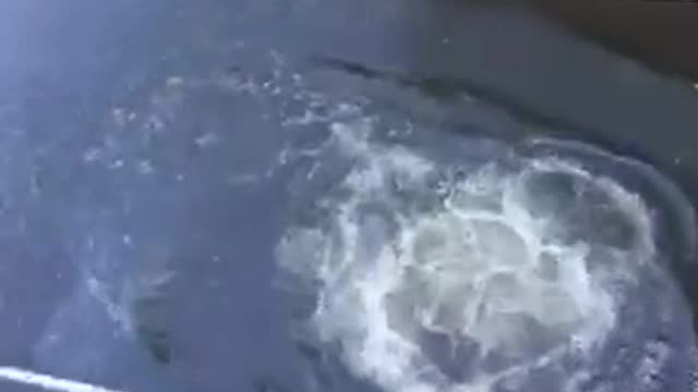 Guy in underwear jumping into water canal off of bridge balcony