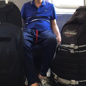 Man in blue smoking with black luggage