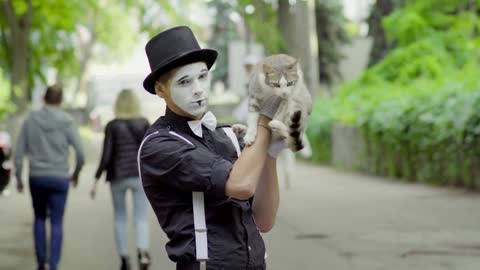 Comic mime joking with cat on the street