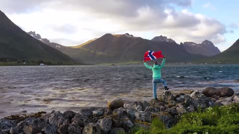 woman with a waving flag of norway on the background of nature