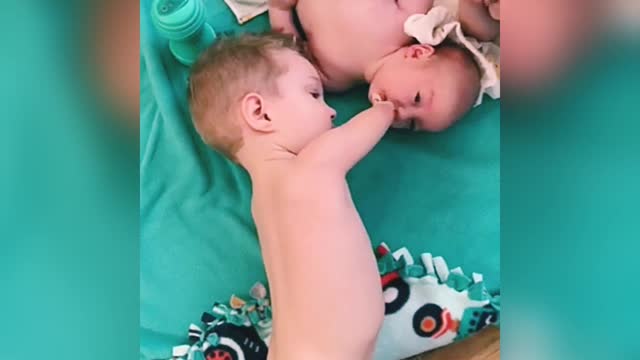 Little boy gives baby brother pacifier