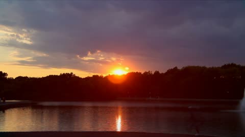 The sun is setting by the lake