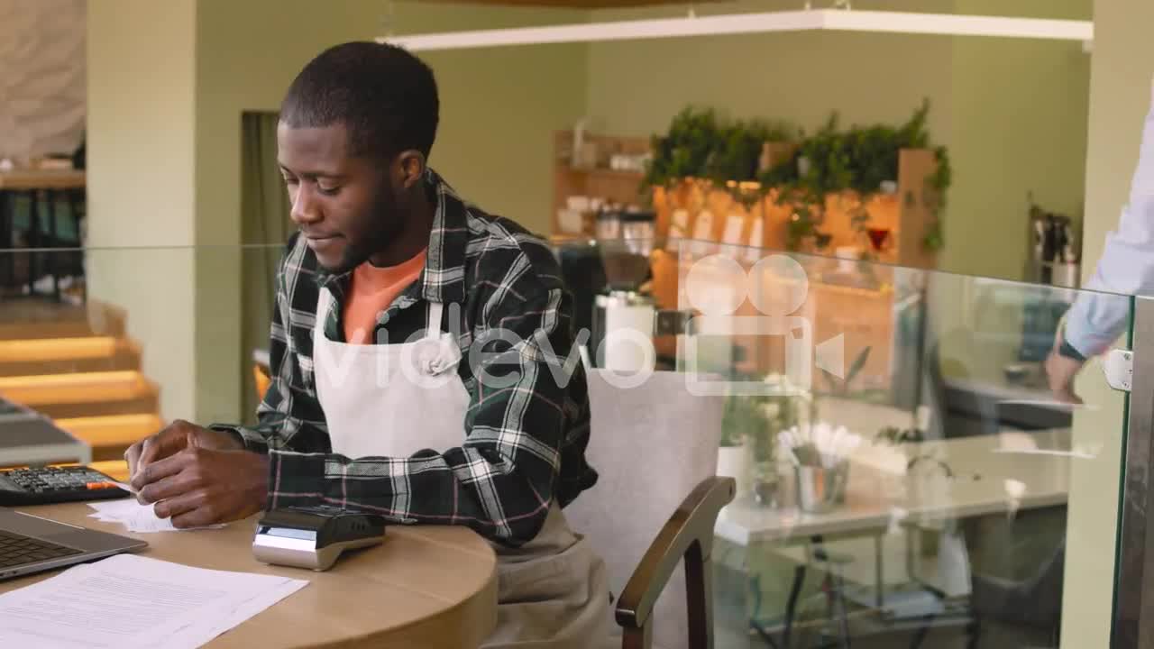 Two Multiethnic Coffee Shop Owners Calculating Finance Bills On Laptop Computer 1