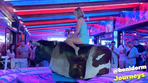 Girl in Beautiful Blue Dress Riding on a Bull in Benidorm 4K