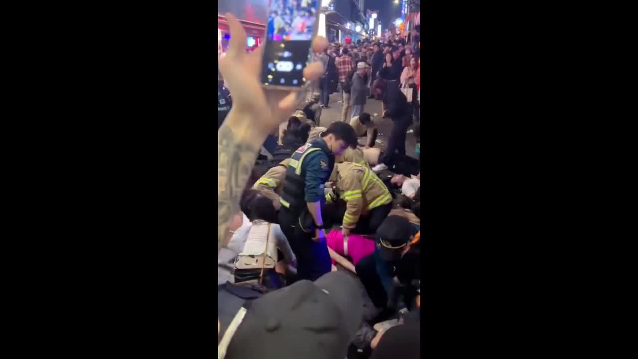 A stampede in Itaewon, A line of people lie on the ground as emergency workers perform CPR.