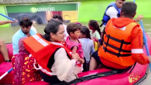 People wade through flooded streets in western India