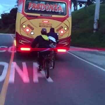 Chicos en bicicleta se enganchan para viajar detrás de un ómnibus