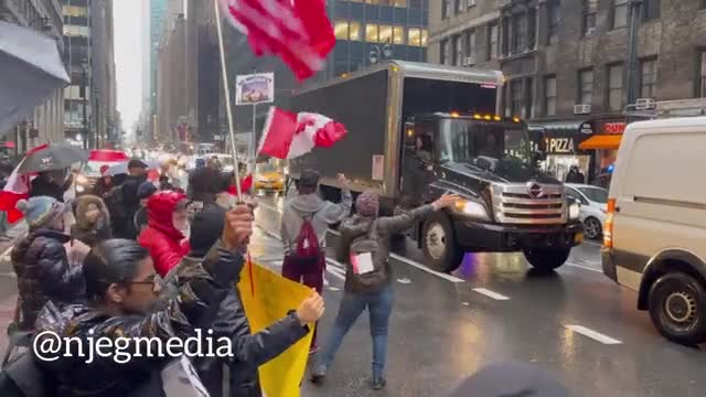 Vehicles honk as they pass protestors outside the Canadian Consulate in New York.