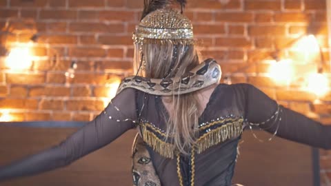 Beautyful circus actress dancing with a snake on the bed