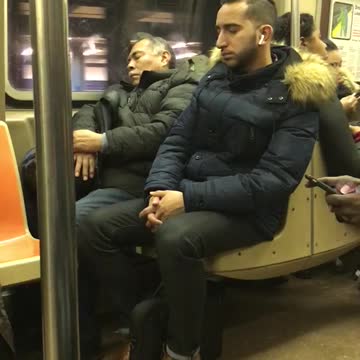 Man in blue jacket leaning on subway seat