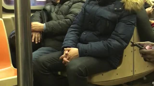 Man in blue jacket leaning on subway seat