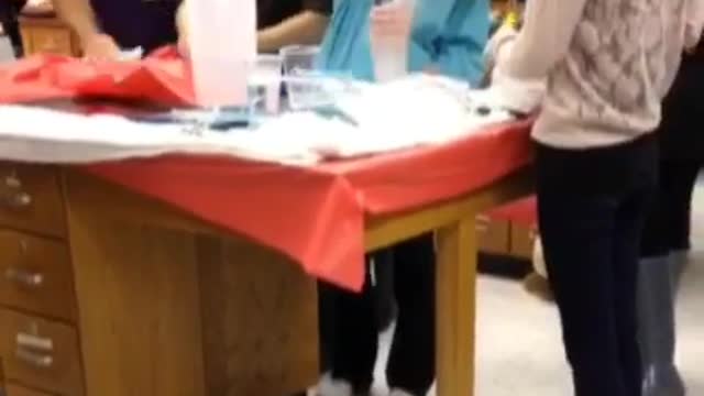 Science experiment explodes in front of girl wearing blue shirt