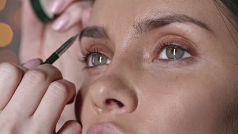 Make-up artist applying make-up on a woman's eyebrow