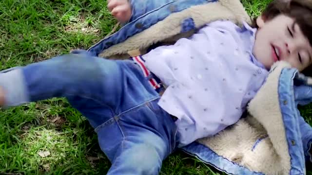 A Kid Playfully Rolling Herself On The Grass