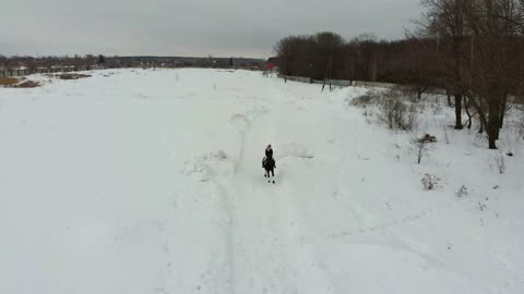 A young woman riding a horse on a snowy field