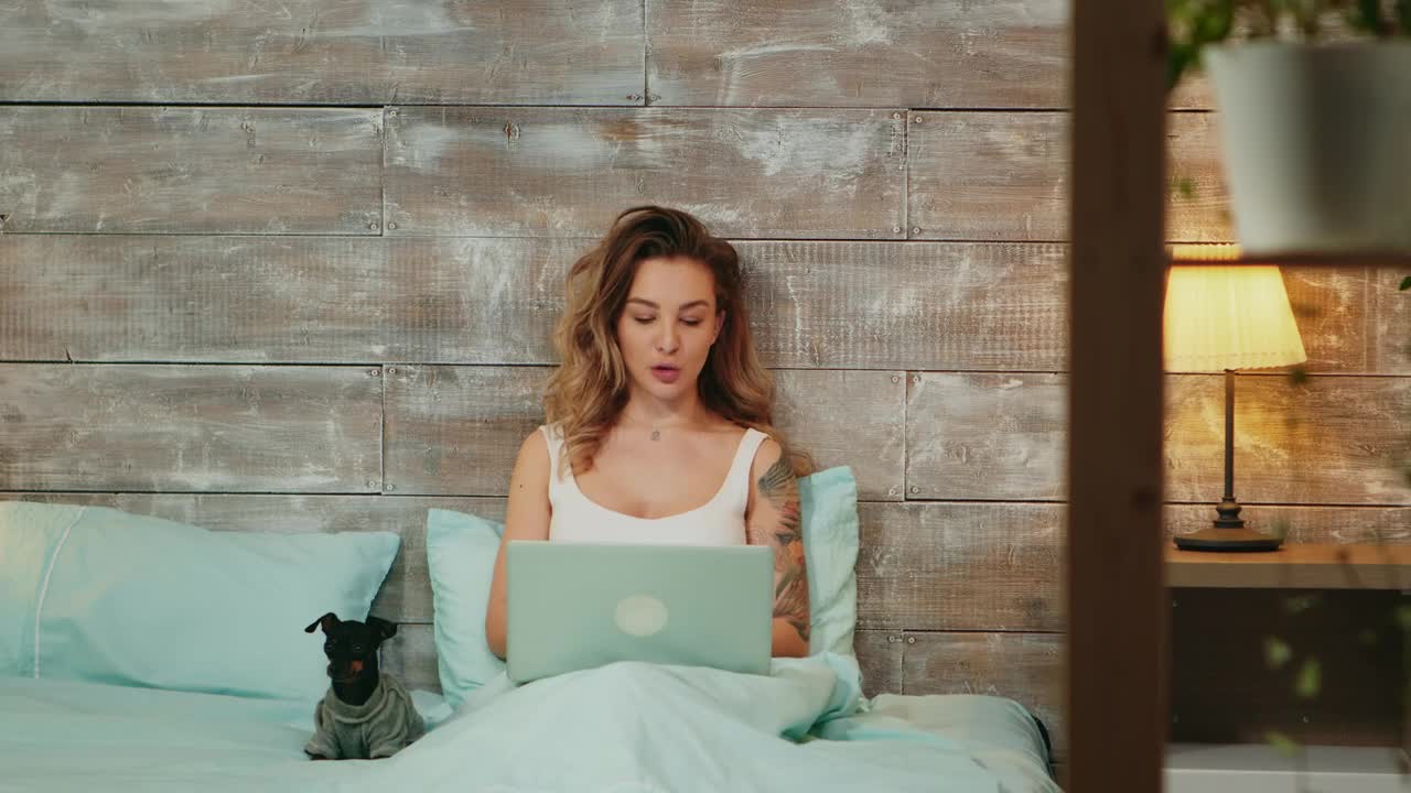 Woman working from her bed with her pet