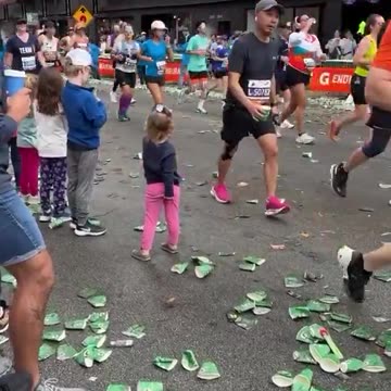 Little girl waits patiently until someone takes her cup of water at the NYC Marathon