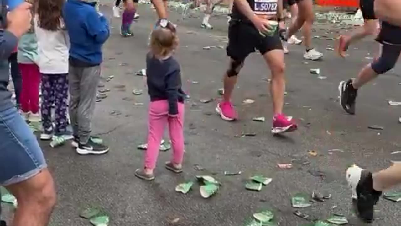 Little girl waits patiently until someone takes her cup of water at the NYC Marathon