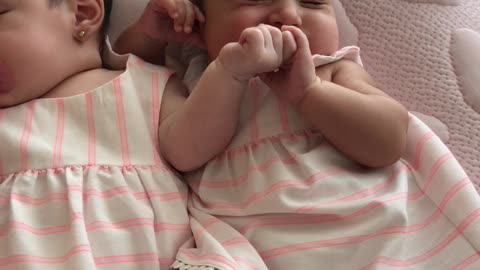 Precious twins hold hands while they sleep