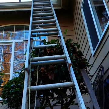 Using an extension ladder stabilizer to climb onto your roof.