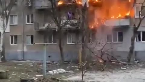 An apartment building burning after getting hit by shelling