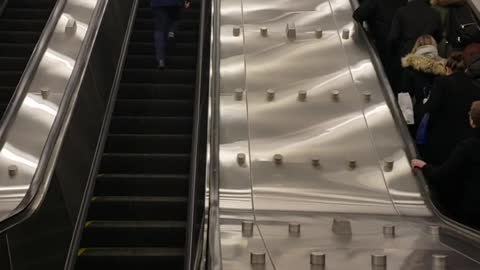 Guy blue jacket running up escalator