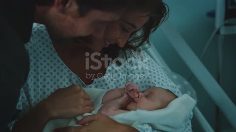 Young parents admiring newborn baby in hospital