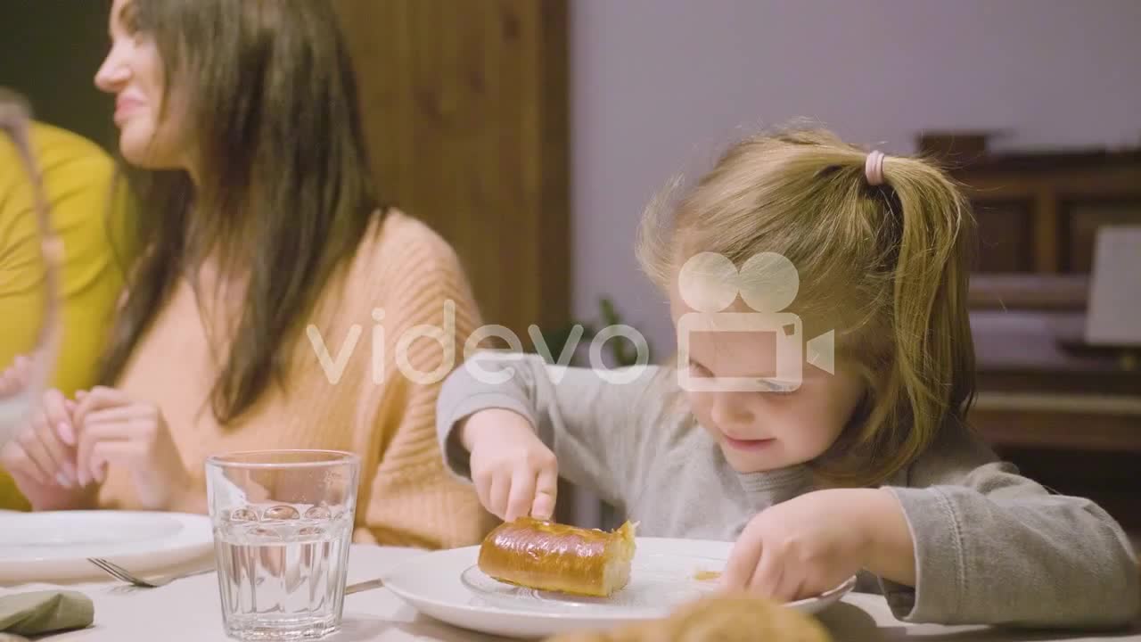 Blonde Little Girl Eating Apple Pie Sitting At The Table While Her Parents Talking During Dinner At