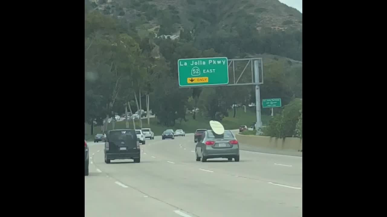 Grey toyota camry car with surfboard on roof