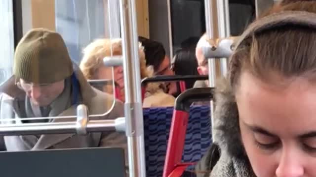 Couple making out on train behind lady with puffy blonde brown hair