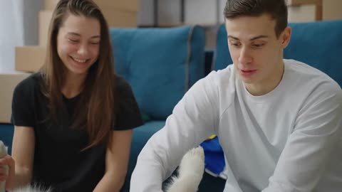 The man strokes the dog's belly with his hand. Smiling boy and girl playing with their dog at home