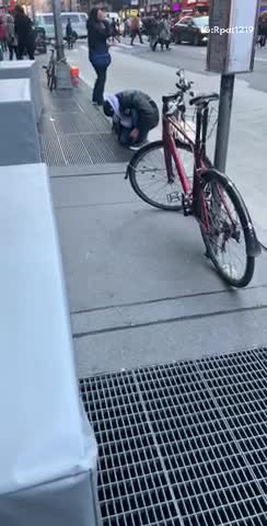 Man fishes through subway grate on the ground
