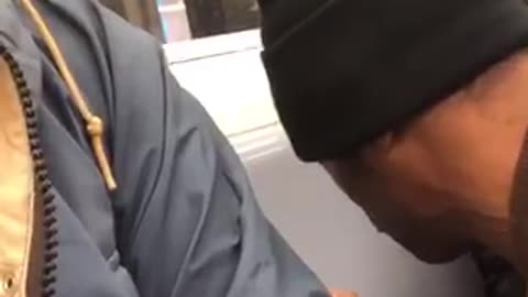 Man in black beanie makes his own beat off of a subway seat and raps