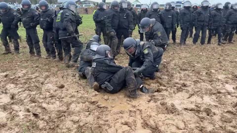 police at protest get stuck in the mud while people taunt them