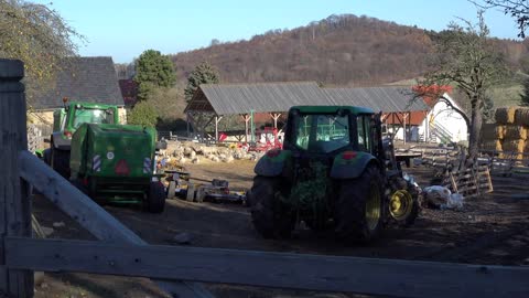 A farm with sheep and a couple of tractors in a rural area