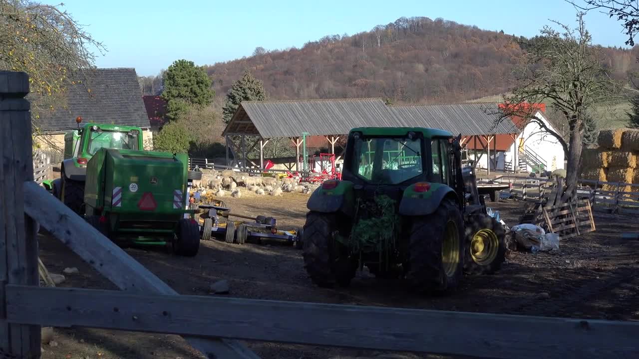 A farm with sheep and a couple of tractors in a rural area