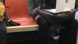 Woman slouches her head and falls asleep on a subway train with her laptop on her lap