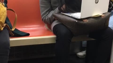 Woman slouches her head and falls asleep on a subway train with her laptop on her lap 