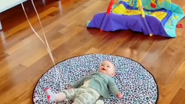 A balloon has been tied in the feet of the little child and he is very happy to see the balloon.