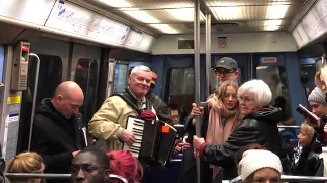 Old man playing accordion on crowded train