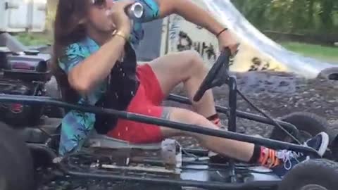 Guy riding go kart gets handed drink and drinks it in slow motion