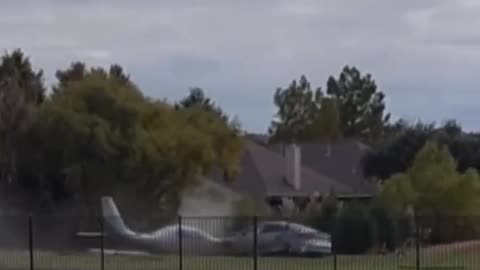 As a small plane overtakes the runway and crashes through a fence into a car