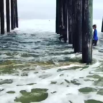 Two girls under wooden pier beams get washed away by high waves