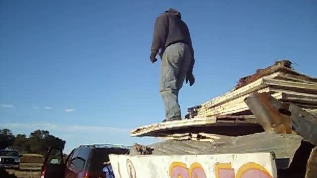 Man Stands on Unstable Pile Of Junk Metal