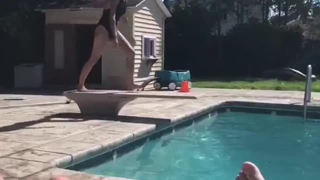 Girl in black bathing suit belly flop into pool