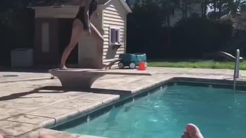 Girl in black bathing suit belly flop into pool