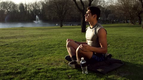 Man doing Yoga by a city lake